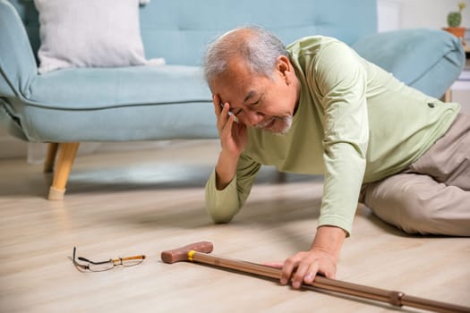 Sick senior old man falling down lying on the ground because stumbled at home alone with wooden walking stick in living room, elderly man grandfather having accident while walk with cane walker