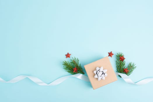 Christmas holiday greeting card with little gift box, stars, ribbon and fir branches, blue background