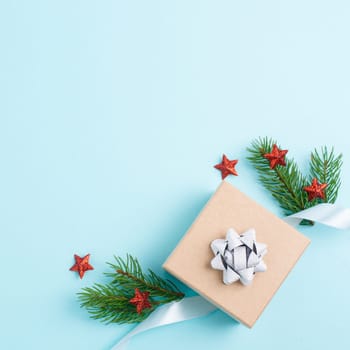 Christmas holiday greeting card with little gift box, stars, ribbon and fir branches, blue background