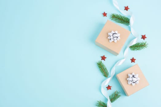 Christmas holiday greeting card with little gift box, stars, ribbon and fir branches, blue background