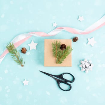 Christmas holiday, wrapping a little gift box with fir branches, pine cones and ribbon