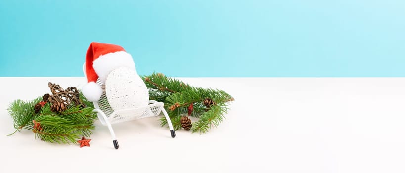 Santa Claus with a red hat sitting in a lounge chair, holiday by the sea, taking a vacation, christmas decoration with fir, cones and stars