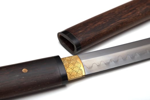 Close-up of a Japanese sword with a handle and a wooden sheath, called Shirasaya, and at the base of the blade, a brass sheath, called habaki, is used to tighten the sword. Soft focus.on white BG.