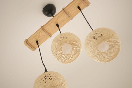Three intricately designed woven lights illuminate a modern space.