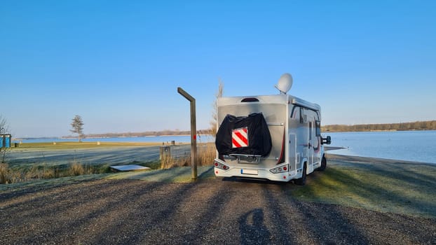 Autumn RV camping. Modern camper van in the late sunny autumn afternoon. Picturesque RV Park.