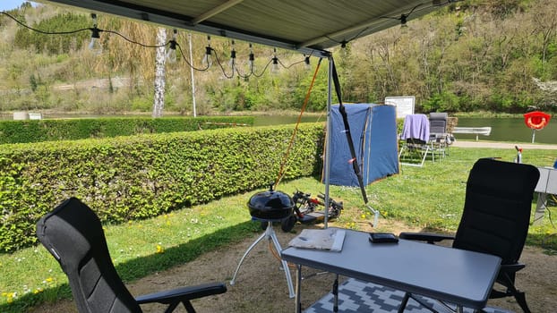 Campervan with awning and air awning and camping table with chairs at campsite