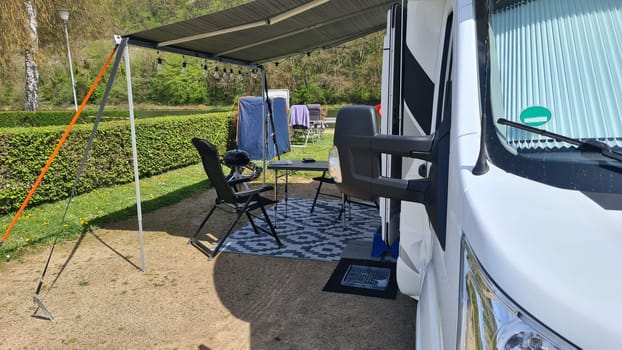 Campervan with awning and air awning and camping table with chairs at campsite