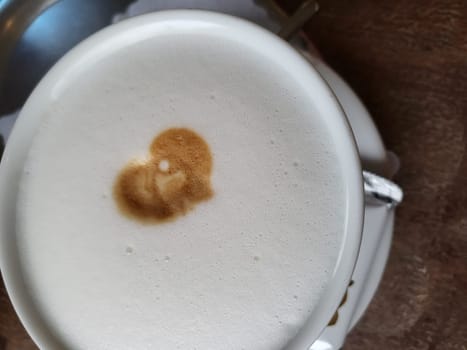 Cup of coffee latte with heart shape and coffee beans on old wooden background