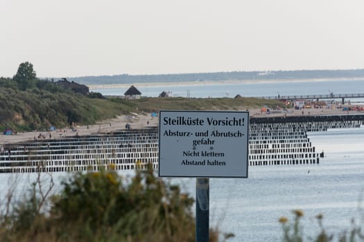 White warning sign with inscription in German - beware of cliffs on the Baltic Sea on the Darss