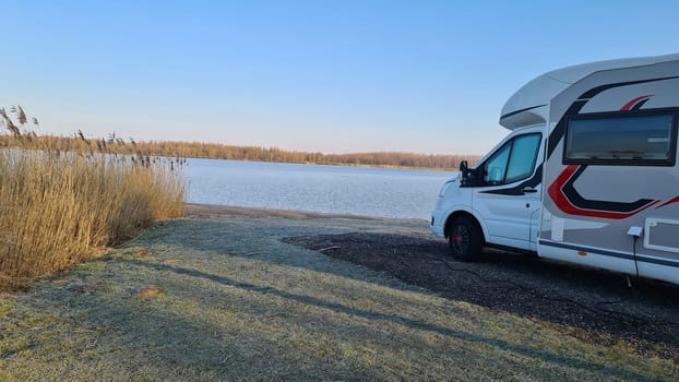 Autumn RV camping. Modern camper van in the late sunny autumn afternoon. Picturesque RV Park.