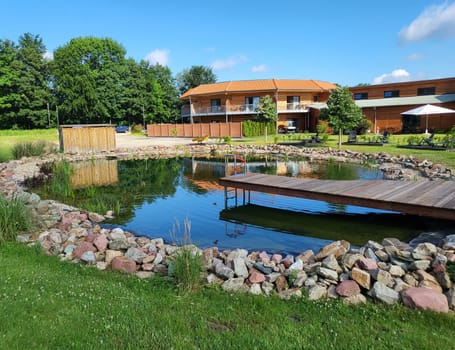 Natural pond of a natural pool with wooden bridge and entrance - natural pool in the background a country hotel