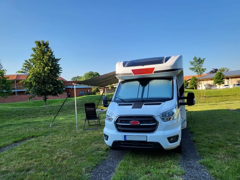 Mobile home with awning and awning and camping table with chairs on the campsite