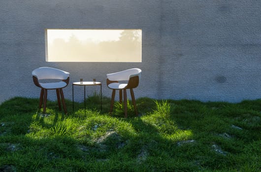 3D Illustration of Two Chairs, Table and Water Glasses Near Window with Bright Sun Light Shining Through Concrete Wall in Grass and Rocks Field.