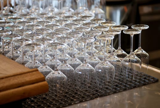Many clean wine glasses are waiting at the counter to be filled.