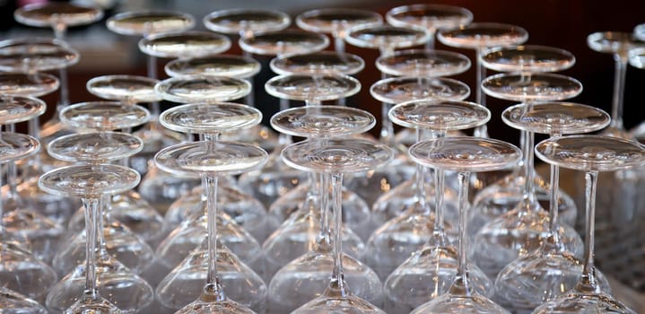 Many clean wine glasses are waiting at the counter to be filled.
