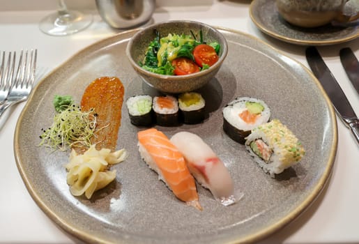 A plate of salad and sushi rolls, fresh raw fish.