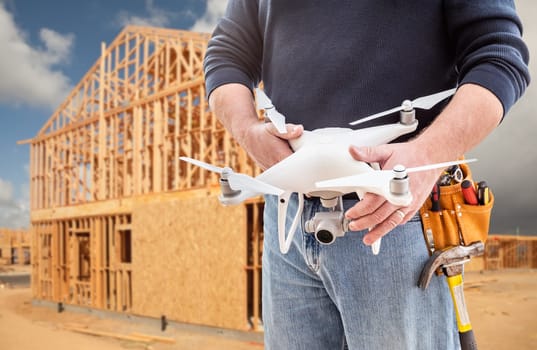 Construction Worker and Drone Pilot With Toolbelt Holding Drone At Construction Site.