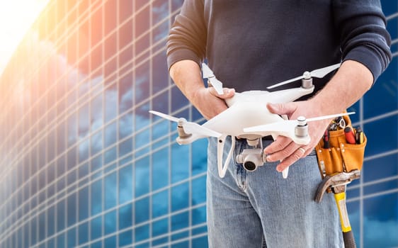 Construction Worker and Drone Pilot With Toolbelt Holding Drone At City High-Rise Building.