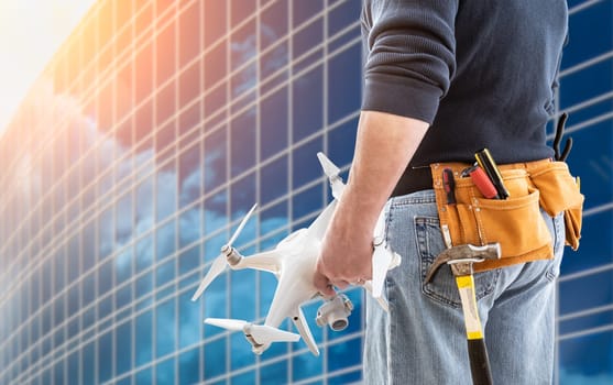 Construction Worker and Drone Pilot With Toolbelt Holding Drone At City High-Rise Building.
