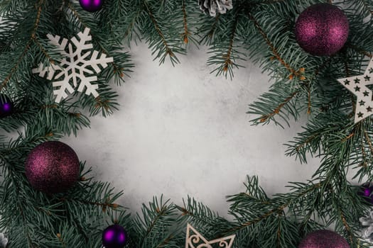 Background image of white concrete surface with branches of Christmas tree, Christmas tree decorations and purple balls. Merry Christmas and Happy New Year. Top view. Copy space