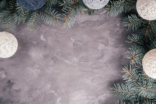 Background image of gray uneven concrete surface with Christmas tree branches and garland of balls. Top view, copy space