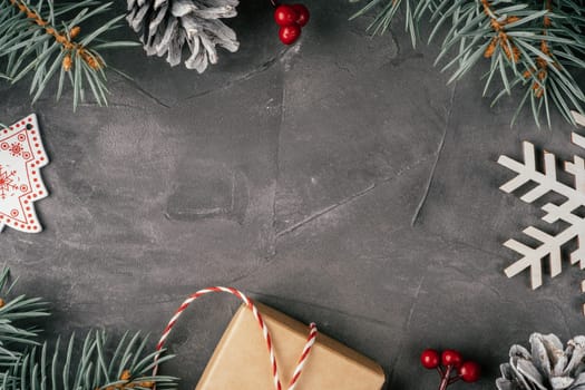 Background image. Frame of Christmas decorations on gray uneven concrete surface. Christmas tree branches, gift, decor, lollipop and snowflake. Merry Christmas and Happy New Year. Top view. Copy space