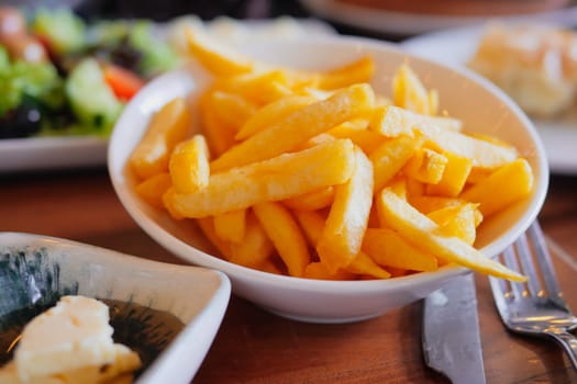 Delicious fries served in a bowl alongside a fresh salad and bread.