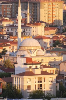 Colorful buildings surround a beautiful mosque during sunset.