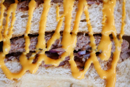 A rich sandwich filled with meat and topped with melted cheese sauce.
