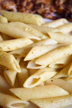 Penne pasta is cooked and seasoned with herbs, creating a savory dish.