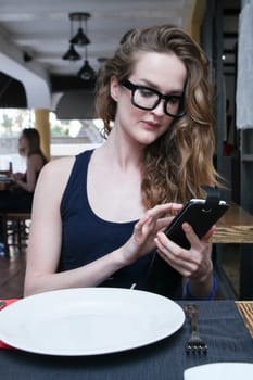 Cute attractive  long hair woman in glasses chat on mobile phone before lunch