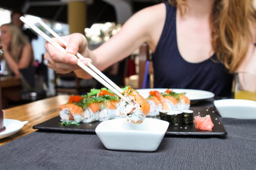 Salmon sushi roll dipping in soya sauce