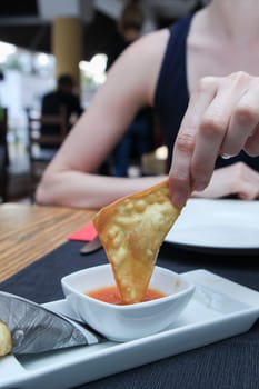 woman hand dipped fried pancake  in sauce