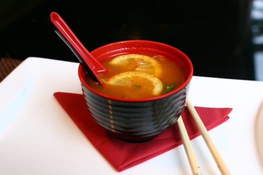 red and black bowl of asian soup miso