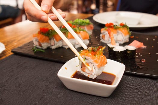 Salmon sushi roll dipping in soya sauce