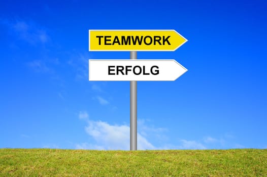 Signpost on meadow in front of blue sky shows teamwork success