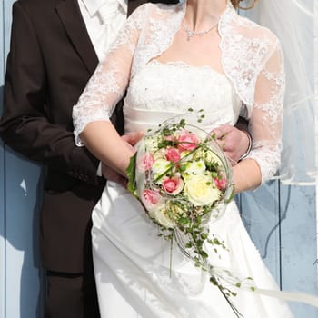 a bride in white wedding dress with a bridal bouquet in hand is held by her groom
