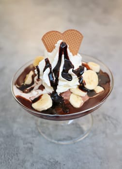 A banana chocolate sundae with whipped cream and chocolate sauce.