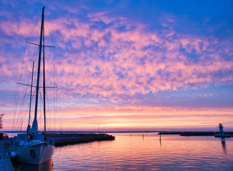 Sailing ship in the harbor of lake Vaettern at sunset. Lighthouse in the background. Landscape shot from Scandinavia
