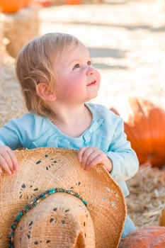Adorable Baby Girl with Cowboy Hat in a Country Rustic Setting at the Pumpkin Patch.