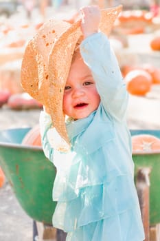 Adorable Baby Girl with Cowboy Hat in a Country Rustic Setting at the Pumpkin Patch.
