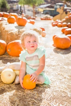 Adorable Baby Girl Having Fun in a Rustic Ranch Setting at the Pumpkin Patch.