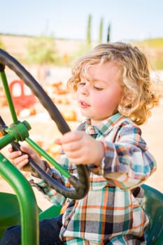 Little Boy Having Fun In A Tractor in a Rustic Ranch Setting at the Pumpkin Patch.