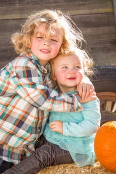 Sweet Little Boy Plays with His Baby Sister in a Rustic Ranch Setting at the Pumpkin Patch.