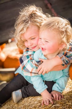 Sweet Little Boy Plays with His Baby Sister in a Rustic Ranch Setting at the Pumpkin Patch.