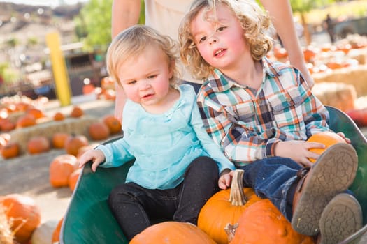 Sweet Little Boy Plays with His Baby Sister in a Rustic Ranch Setting at the Pumpkin Patch.