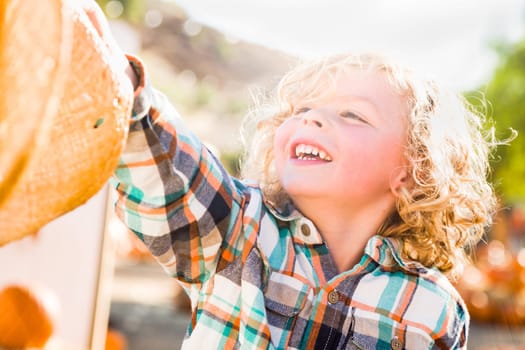 Little Boy Sitting With A Cowboy Hat in a Rustic Ranch Setting at the Pumpkin Patch.