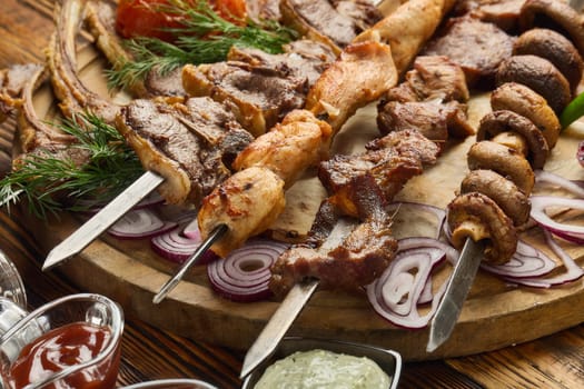 Various grilled meats. Shashlik from different meats on barbecue skewers with vegetables and lavash on wooden board. Top view. Food background. Serving food