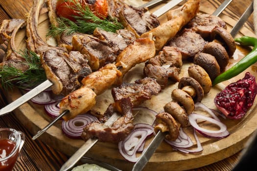 Various grilled meats. Shashlik from different meats on barbecue skewers with vegetables and lavash on wooden board. Top view. Food background. Serving food
