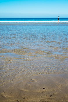 calm soft waves lashing onto ballybunion beach in county kerry ireland with wading woman